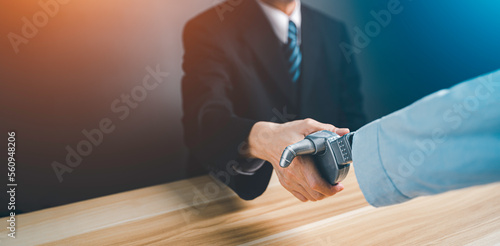 Hand of a businessman in a suit shaking hands and make deal with a droid robot. Concept of innovation in business with artificial intelligence.