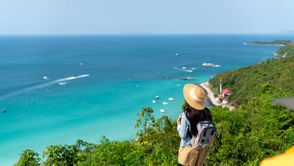 Asian woman with backpack solo travel on tropical island mountain peak in summer sunny day. Attractive girl enjoy and fun outdoor lifestyle looking beautiful nature of ocean on beach holiday vacation.