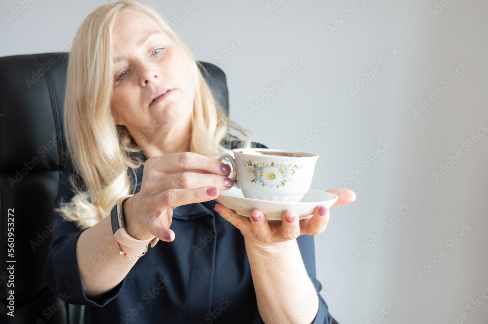 Woman holding a cup of coffee with a saucer. Selective focus on the cup Woman holding a cup of coffee with a saucer. Selective focus on the cup