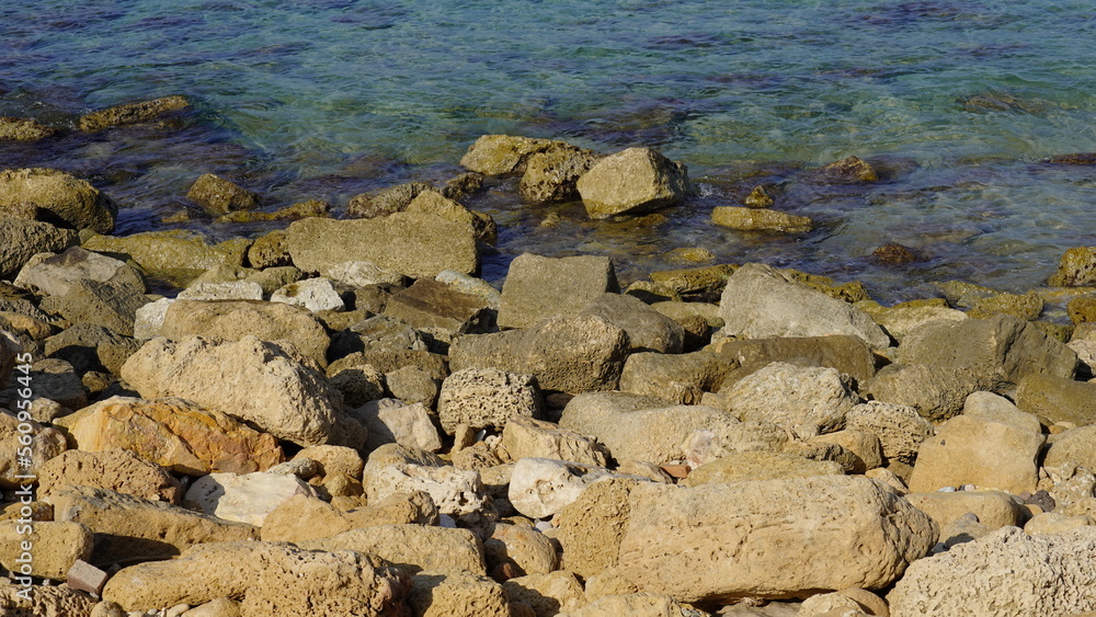 Cobble pieces of marble rock near water edge in Caesarea Maritima National Park, Israel.