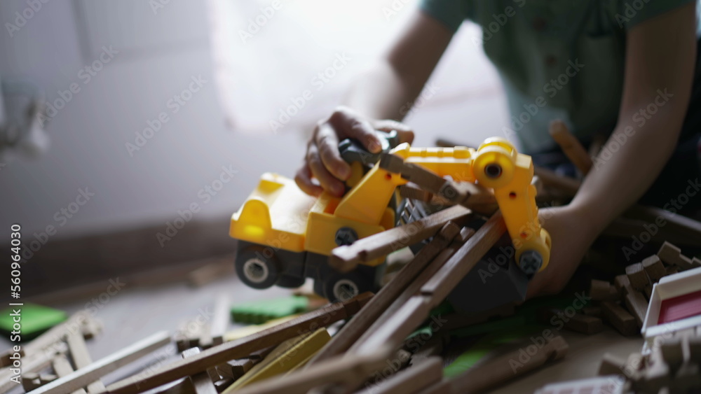 Child destroying wooden home toy with small bulldozer tractor. One little boy destroyer playing at home in playroom Child destroying wooden home toy with small bulldozer tractor. One little boy destroyer playing at home in playroom