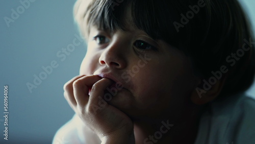 Closeup child face with hand in in chin watching screen hypnotized by online content