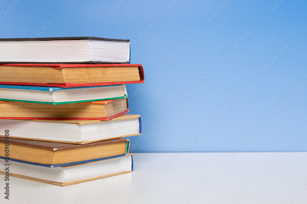 Stack of books in the colored cover lay on the wooden table and blue backround. Education learning concept Stack of books in the colored cover lay on the wooden table and blue backround. Education learning concept