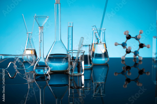 Laboratory investigations concerning test and medicine against covid. Glass tubes, microscope and beakers on blue bokeh background.