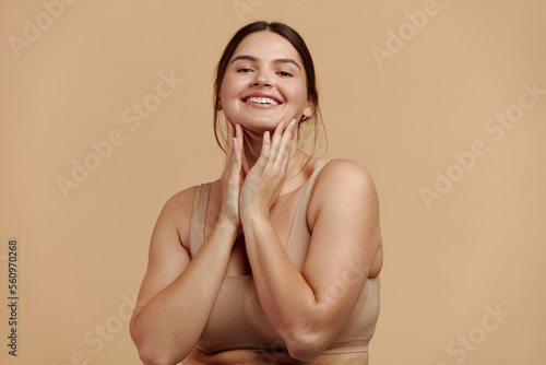Smiling Woman Touching Face. Waist up Portrait of Attractive Woman Touching her Skin and Smiling While Applying Moisturiser. Woman Appearance and Skin Care Concept 
