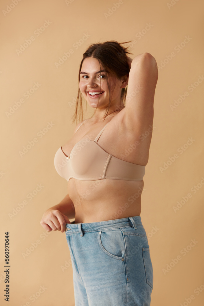 Plus Size Woman in Jeans. Overweight Smiling Woman Demonstrating Weight Loss. Happy Girl Showing Large Jeans And Looking At Camera Plus Size Woman in Jeans. Overweight Smiling Woman Demonstrating Weight Loss. Happy Girl Showing Large Jeans And Looking At Camera