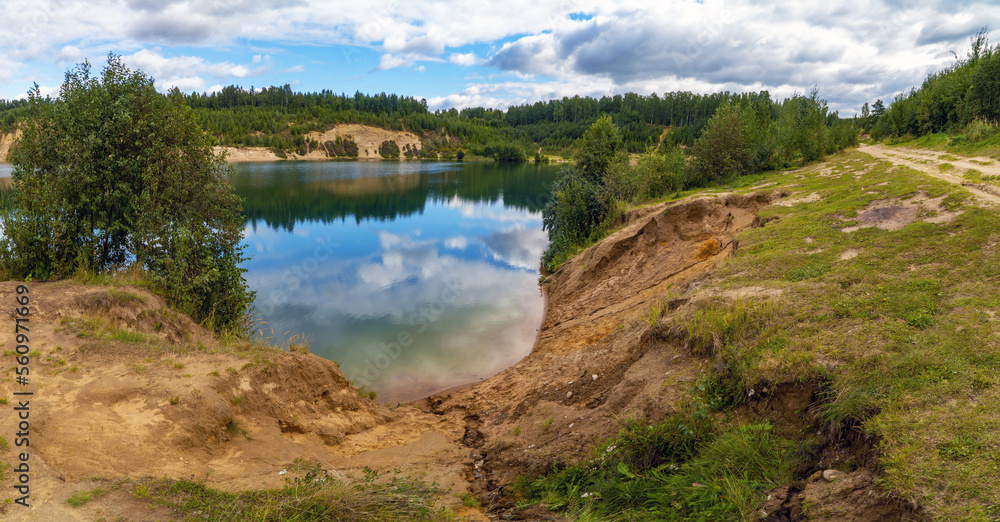 Fototapeta premium Snow - white clouds are reflected in the lake . Panorama.