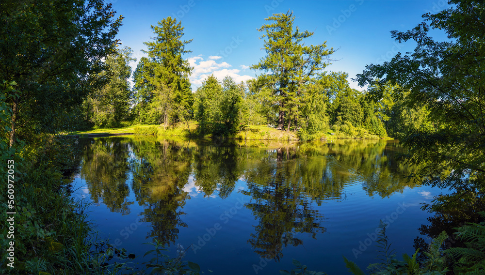 A picturesque lake shore with a mirror - like surface of water . A picturesque lake shore with a mirror - like surface of water .