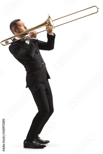 Obraz na płótnie Full length profile shot of a man in a black suit playing a trombone