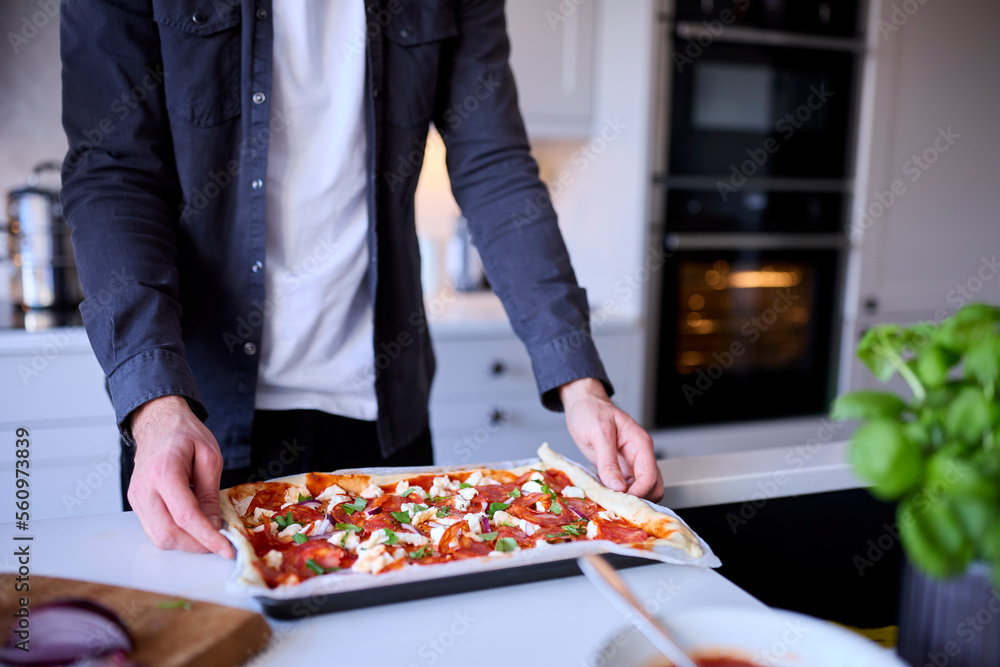 Close Up Of Man In Kitchen At Home With Homemade Pizza Ready To Be Baked In Oven