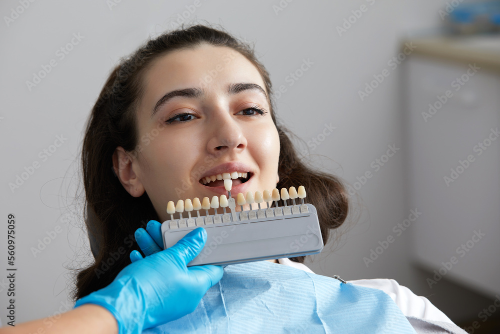Dentist choosing color tone of tooth enamel for patient. Dentist