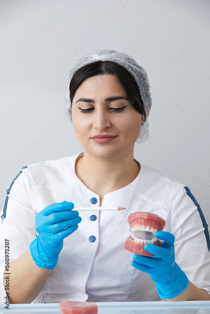Dentist showing model of human jaw with wire braces and aligners to compare Dentist showing model of human jaw with wire braces and aligners to compare