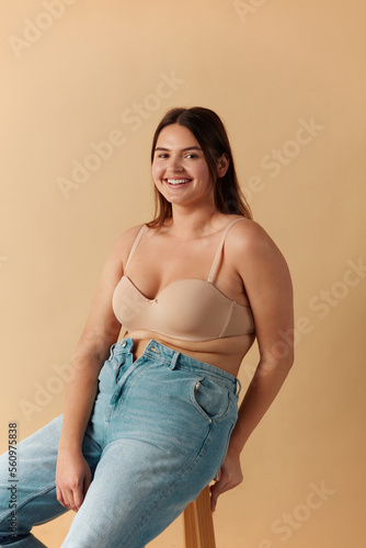 Full Figured Woman. Happy Curvy Oversize Woman In Beige Lingerie Sitting Chair At Studio. Body Imperfection, Body Acceptance, Body Positive And Diversity Concept  photo