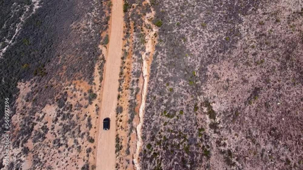 Tracking shot flying forwards over a car driving on a dirt road, in Cloetesberg, South Africa, on edge of the klein karoo semi desert region and garden routes. Tracking shot flying forwards over a car driving on a dirt road, in Cloetesberg, South Africa, on edge of the klein karoo semi desert region and garden routes.