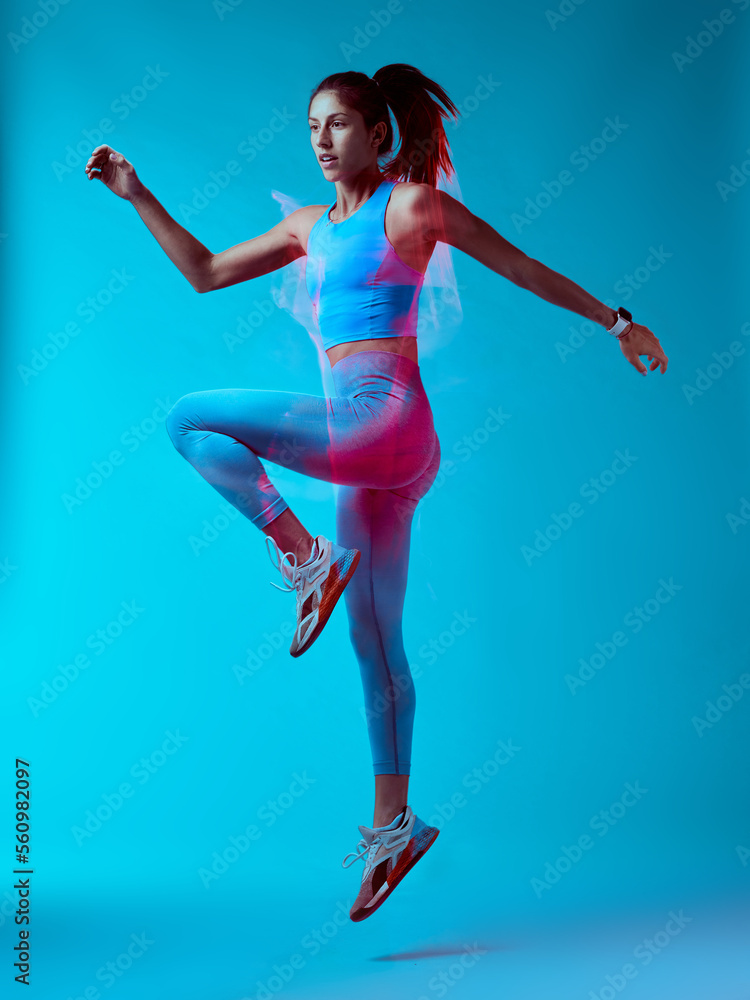 Obraz premium A fit sportswoman jumping and doing exercises. Long exposure capture movement.