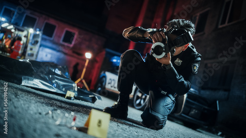Tilted Shot: Asian Policeman Taking Pictures of Marked Evidence, the Victim's Bagged Corpse in the Background. Police Officer Documenting Bloody Glasses on the Floor For Further Investigation