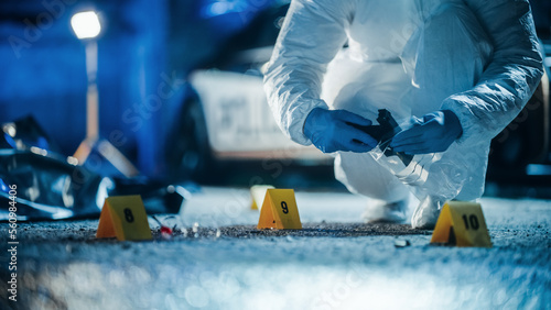 Forensics Specialists Starting to Pack Evidence on Crime Scene After a Tragic Ending of a Violent Gun Fire Exchange Between Gang Members. Empty Handgun is the Murder Weapon Used to Shoot the Victims photo