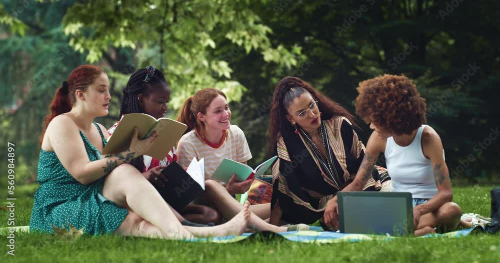 Diverse Female Friends Discussing and Using Notebooks and a Laptop. Group of Multiethnic Female Students Working on a Project for University Outdoors and Enjoying the Good Summer Weather Diverse Female Friends Discussing and Using Notebooks and a Laptop. Group of Multiethnic Female Students Working on a Project for University Outdoors and Enjoying the Good Summer Weather