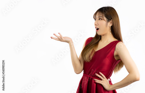 Asian woman in red elegant dress smiling and hand pointing on white background. Happy Valentine.