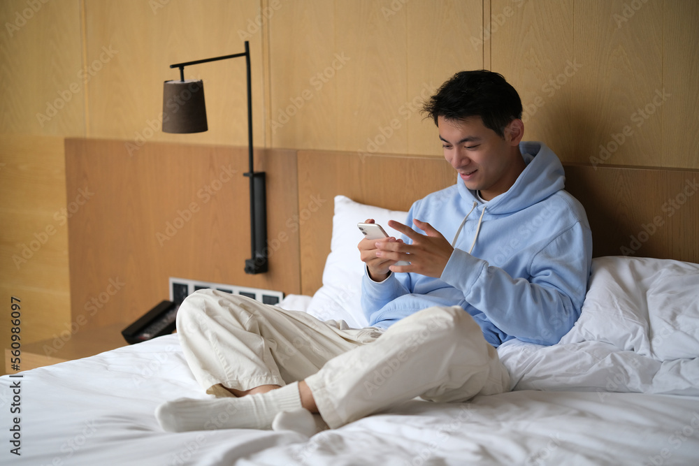 handsome smile Asian young man use phone on bed handsome smile Asian young man use phone on bed