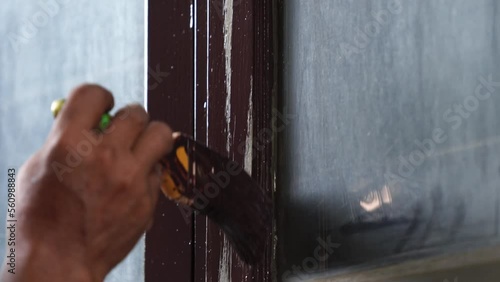 Close-up of a worker painting old wooden window frames