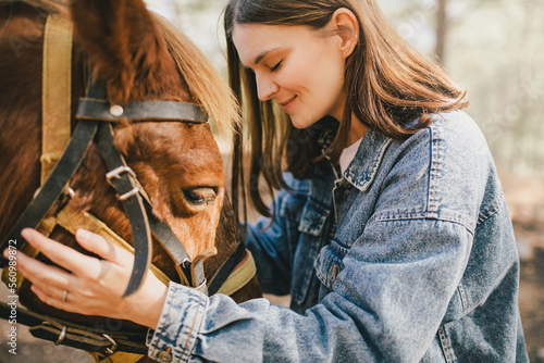 Photographie A young woman hugging a horse.