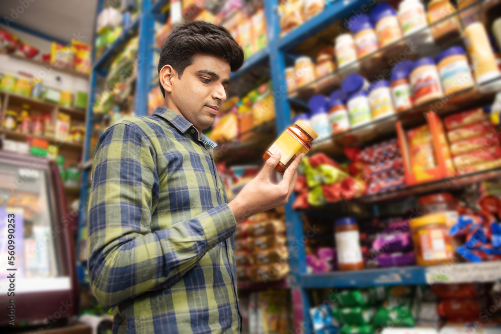 Young handsome indian man pick grocery item from shelf at supermarket , Asian male shopping at grocery store.
