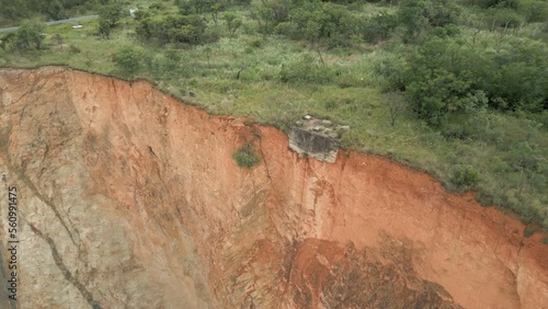 Aerial descends to concrete foundation at edge of vertical rock cliff photo