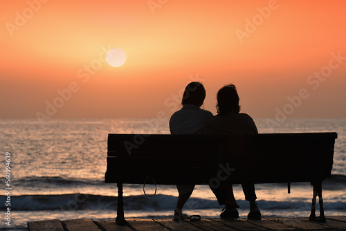 Back view of a couple silhouette, watching sunset on the beach