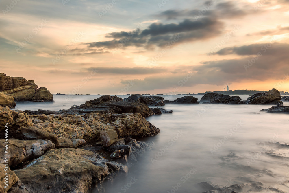 Scenic view of rocks in sea against cloudy sky with Nojimasaki lighthouse in background Scenic view of rocks in sea against cloudy sky with Nojimasaki lighthouse in background