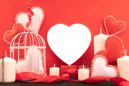 Composition pour la Saint-Valentin avec un c≈ìur transparent, un cage √† oiseaux et des bougies.