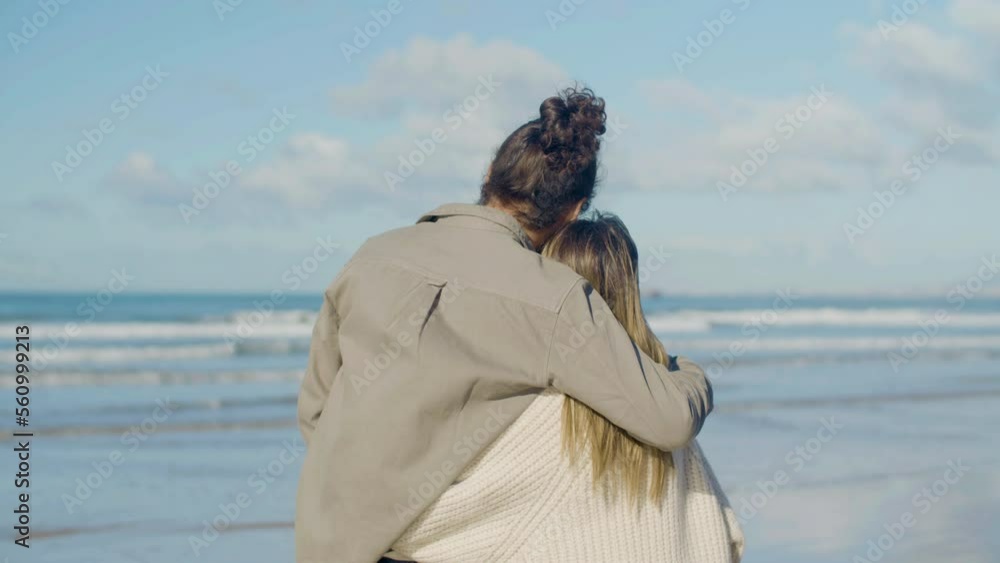 Romantic Caucasian couple spending time at beach on warm autumn day. Tall guy with beard and man bun embracing pretty blonde woman while couple standing and enjoying sea view. Romance, travel concept Romantic Caucasian couple spending time at beach on warm autumn day. Tall guy with beard and man bun embracing pretty blonde woman while couple standing and enjoying sea view. Romance, travel concept