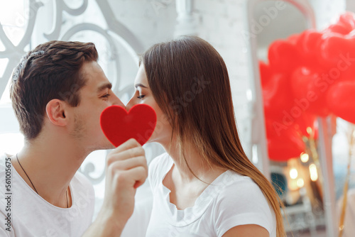 Two young people kissing behind a paper heart. Celebrating Saint Valentine's day. photo