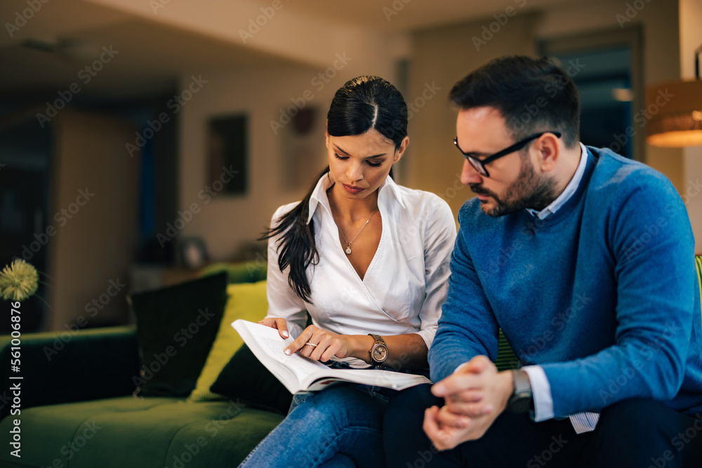 Female and male employees reading notes from notebook, sitting at the office. Female and male employees reading notes from notebook, sitting at the office.
