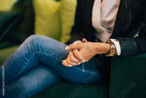 Hands of a businesswoman, sitting on the couch, elegantly dressed. © bnenin