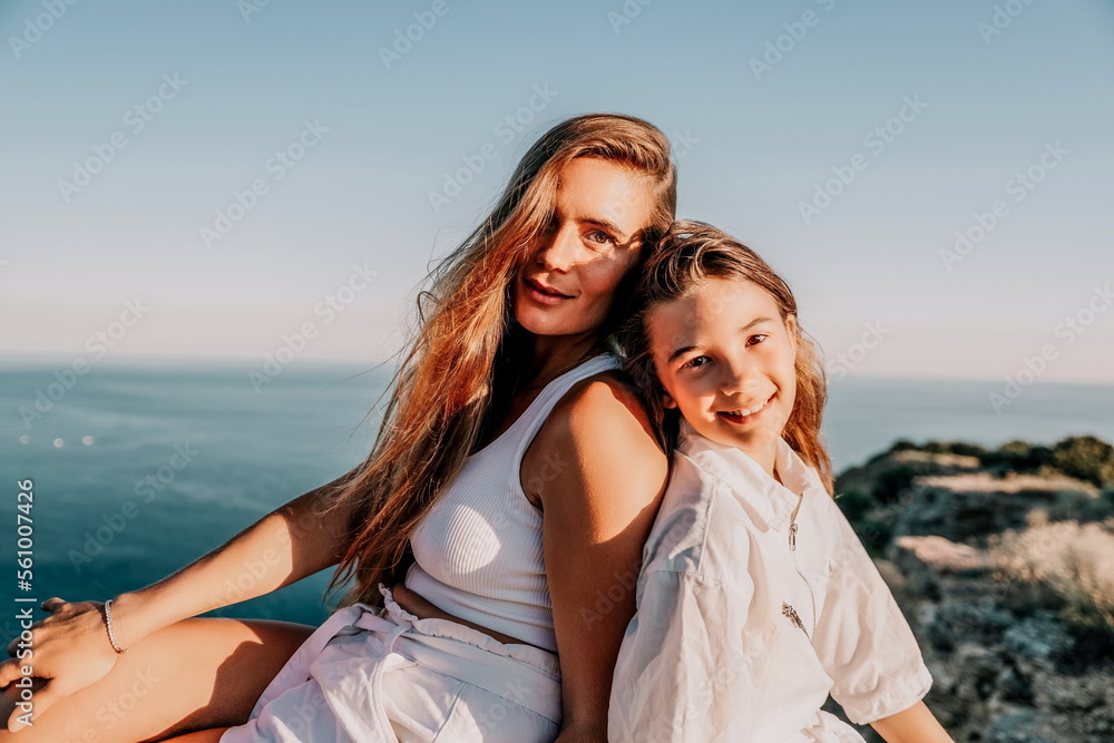 Sea family vacation together, happy mom and teenage daughter hugging and smiling together over sunset sea view. Beautiful woman with long hair relaxing with her child. Concept of happy friendly family Sea family vacation together, happy mom and teenage daughter hugging and smiling together over sunset sea view. Beautiful woman with long hair relaxing with her child. Concept of happy friendly family