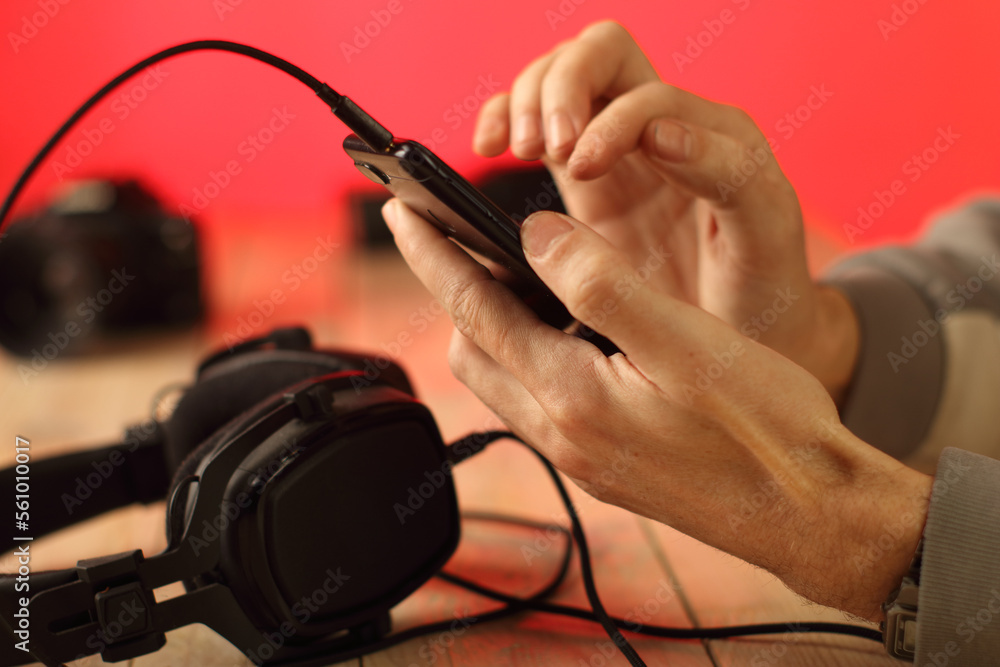 person holds smartphone in hand over stereo headphones person holds smartphone in hand over stereo headphones