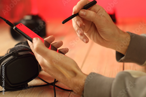 a person writes with a stylus on a smartphone over headphones