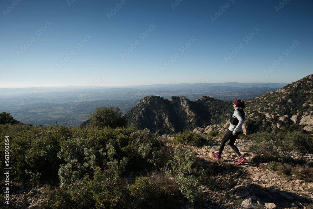Athlete woman, runs to the top of a mountain where there is a cross, in Catalonia, Spain.