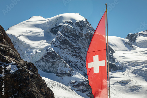 Swiss flag and Bernina mountain range with glaciers in the Alps, Switzerland
