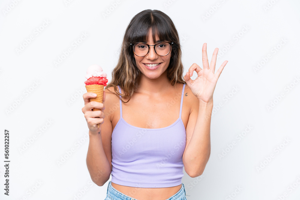 Young caucasian woman with a cornet ice cream over isolated white background showing ok sign with fingers Young caucasian woman with a cornet ice cream over isolated white background showing ok sign with fingers
