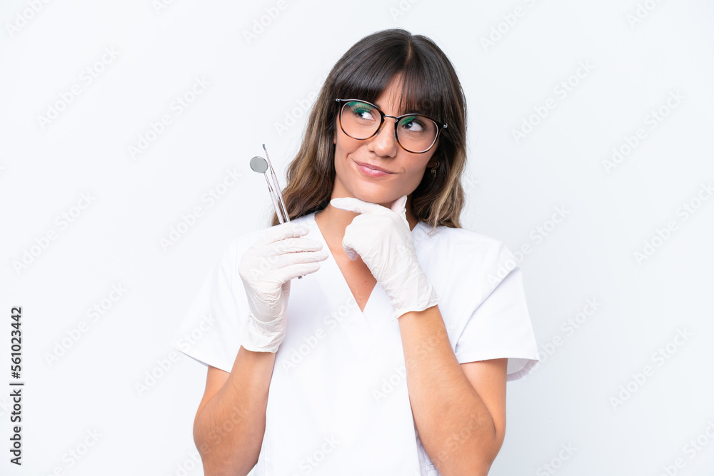 Dentist caucasian woman holding tools isolated on white background having doubts Dentist caucasian woman holding tools isolated on white background having doubts