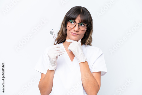 Dentist caucasian woman holding tools isolated on white background having doubts