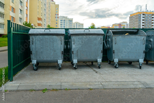Modern metal containers for separate garbage collection. Garbage cans in the city on the background of a house. Environmental disaster, problems of waste removal, collection and disposal in a big city