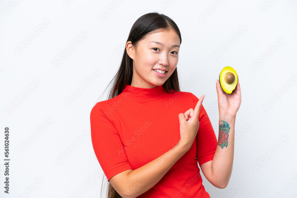 Young Asian woman holding an avocado isolated on white background and pointing it Young Asian woman holding an avocado isolated on white background and pointing it