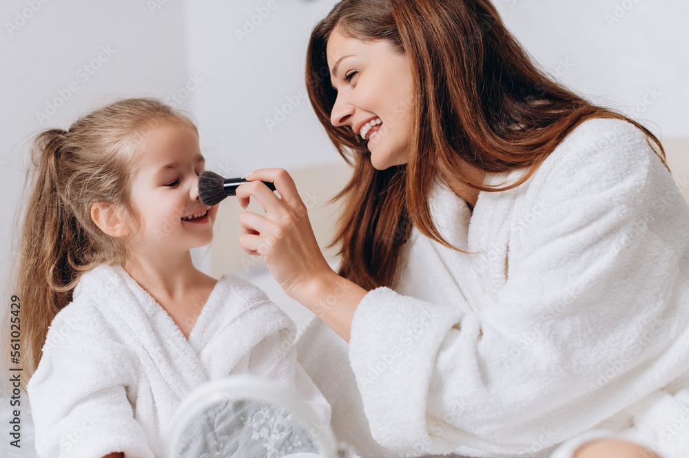 Cute preschool girl and her mom doing makeup for each other at home. Close up.
