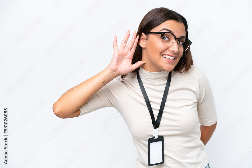 Young caucasian woman with ID card isolated on white background listening to something by putting hand on the ear Young caucasian woman with ID card isolated on white background listening to something by putting hand on the ear