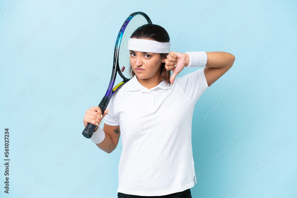 Young tennis player woman isolated on blue background showing thumb down with negative expression Young tennis player woman isolated on blue background showing thumb down with negative expression