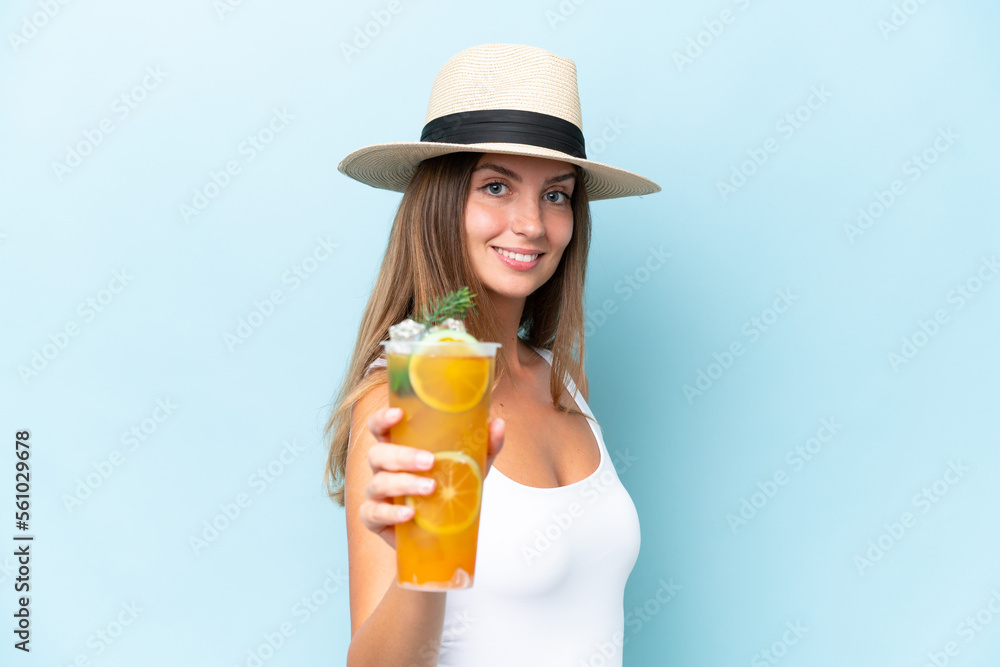 Young beautiful woman holding a cocktail isolated on blue background with happy expression