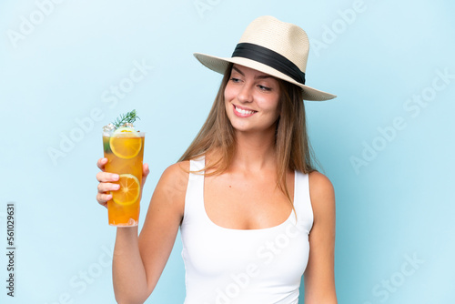 Young beautiful woman holding a cocktail isolated on blue background with happy expression